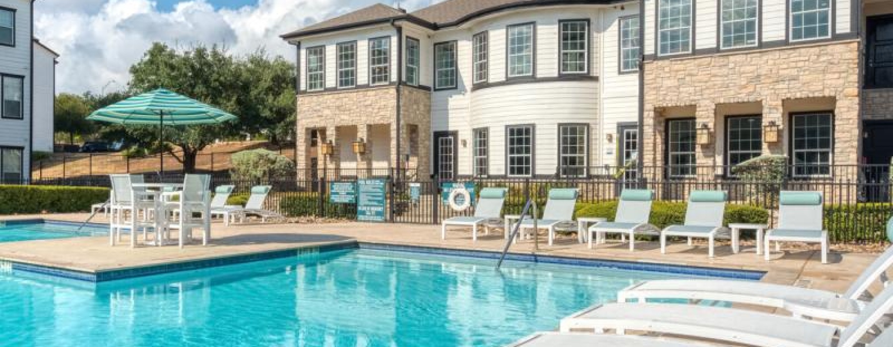 pool surrounded with lounge seating and a building in the background